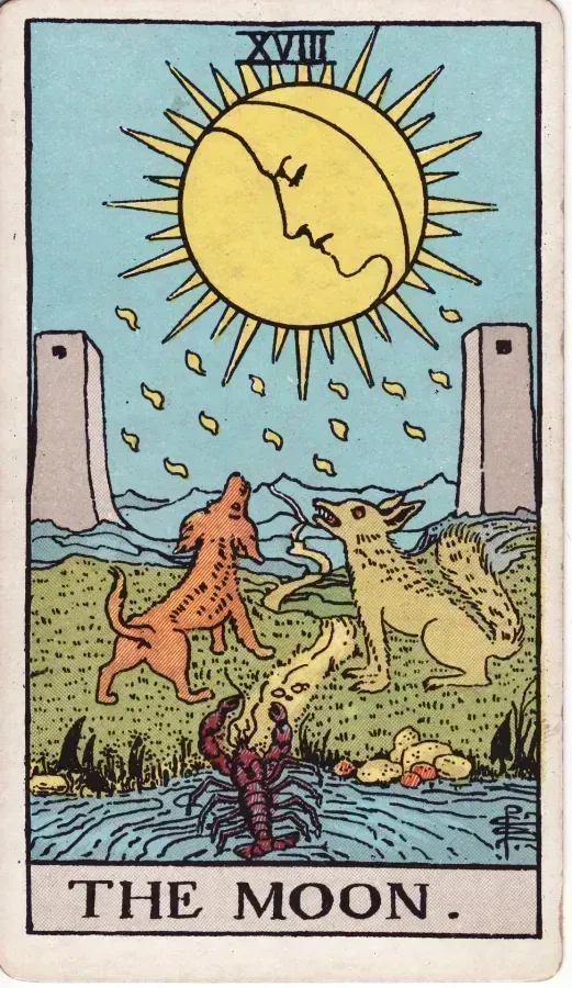 La Luna con rostro en la parte superior de la carta, un cangrejo saliendo del agua, dos torres a los lados y un camino sinuoso entre ellas